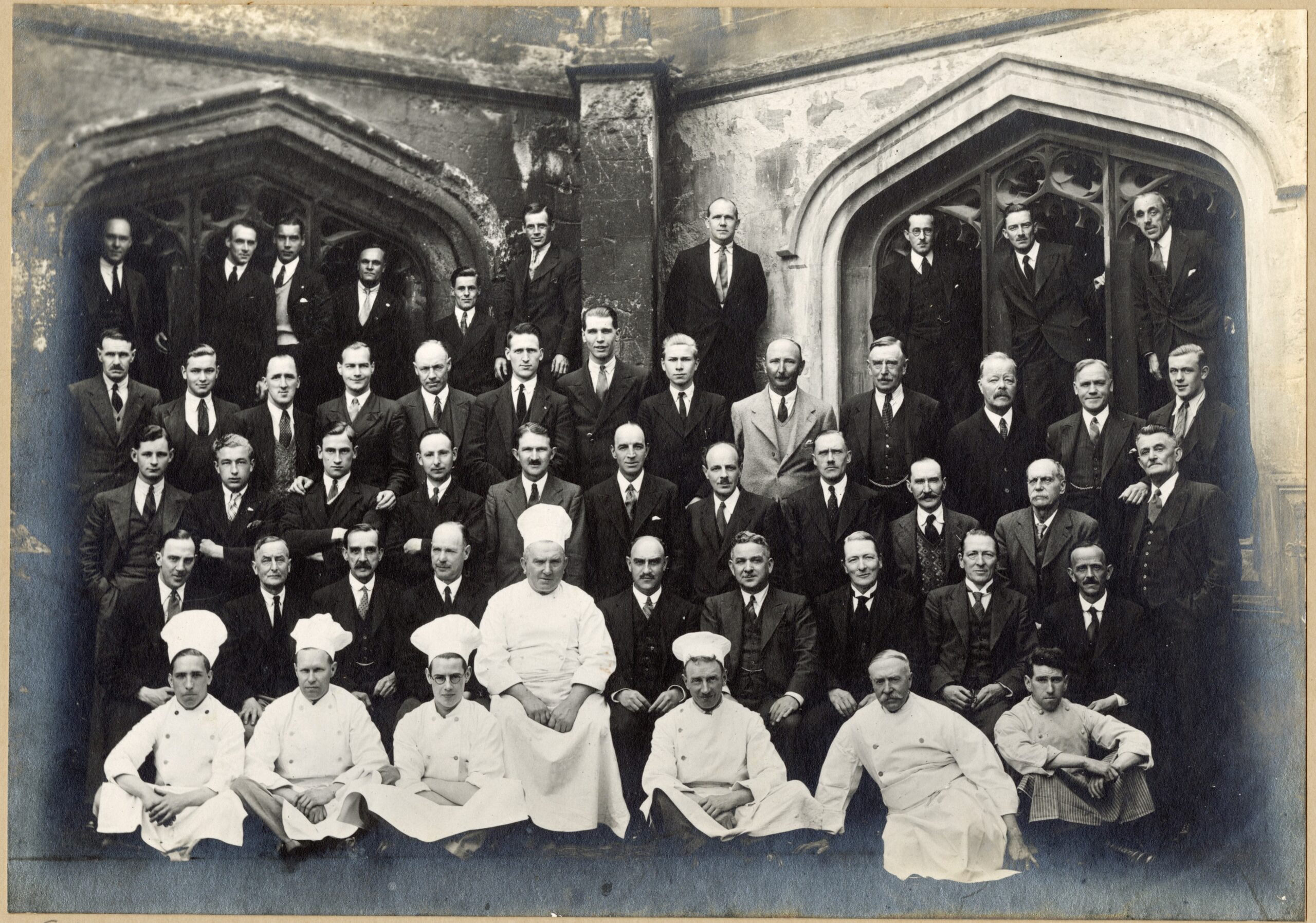 Black-and-white formal photograph of Magdalen College staff, taken in the Cloisters in 1935.